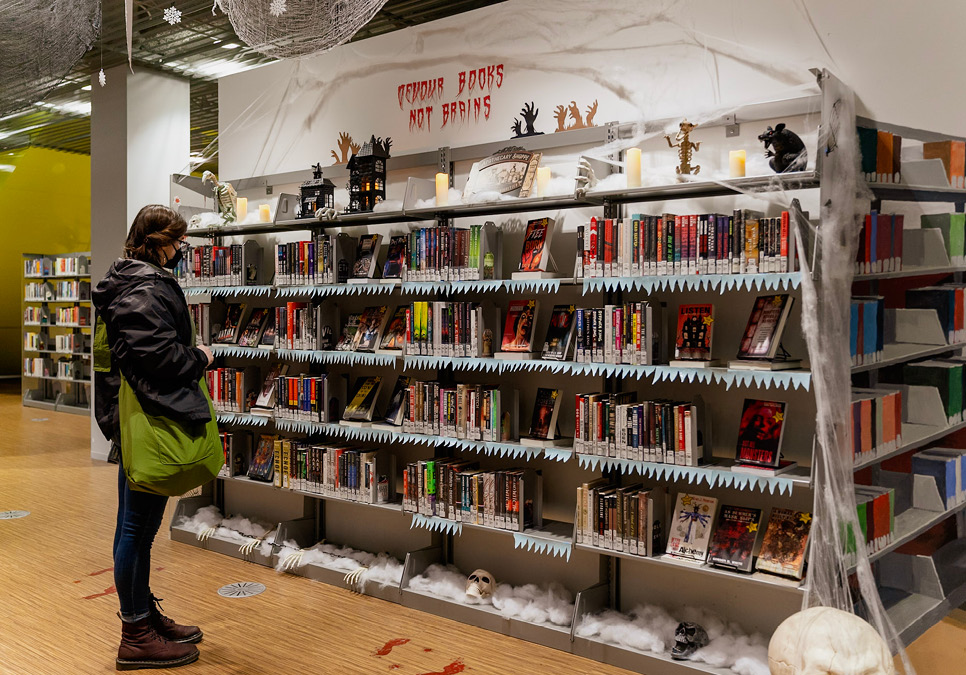 Person standing next to large rack of books.