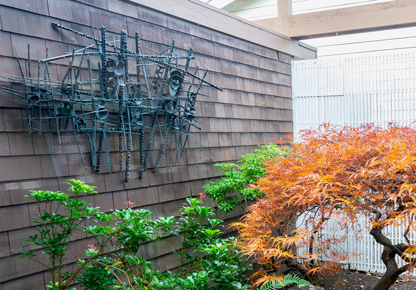 Metallic sculpture wall mounted in an exterior courtyard